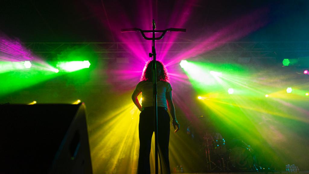 Derby Motoreta Burrito Cachimba actuando firme frente a un escenario con luces de distintos colores